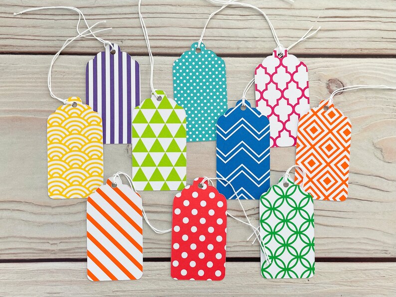 May include: Ten colourful gift tags with different geometric patterns. The tags are made of paper and have a string attached to them. The patterns include stripes, polka dots, zigzags, and more.