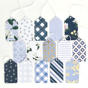 May include: A set of 15 gift tags with various blue and white patterns. The tags are made of cardstock and have a scalloped edge. The patterns include floral, geometric, and plaid designs.