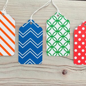 May include: Four gift tags with different patterns. The tags are white with orange and white stripes, blue with white zigzags, white with green circles, and red with white polka dots.