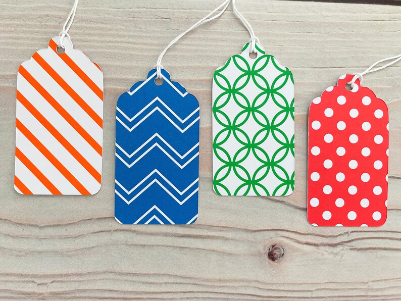 May include: Four gift tags with different patterns. The tags are white with orange and white stripes, blue with white zigzags, white with green circles, and red with white polka dots.