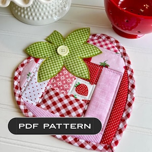 Puede incluir: Un salvamanteles acolchado con forma de fresa con una hoja de cuadros verdes y un botón. La almohadilla presenta un diseño de patchwork con telas rojas y rosas, incluyendo lunares y cuadros de vichy. El texto en la imagen dice "PDF PATTERN".