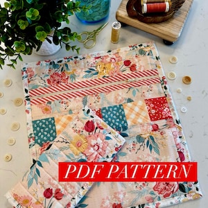 May include: A floral quilted placemat and matching coaster set with a patchwork design. The placemat features a zipper pocket and the text "PDF PATTERN" in a red banner. Additional sewing notions include a wooden swan, buttons, and scissors.