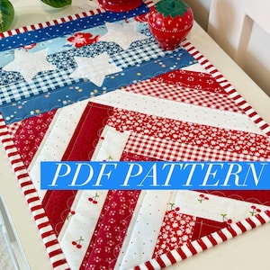 May include: A patriotic-themed quilted table runner featuring red, white, and blue fabrics. The design includes white stars, gingham, floral patterns, and cherry prints. The text "PDF PATTERN" is displayed on the runner.