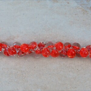 May include: A red glass bead bracelet with silver clasps. The beads are clear with red flecks.