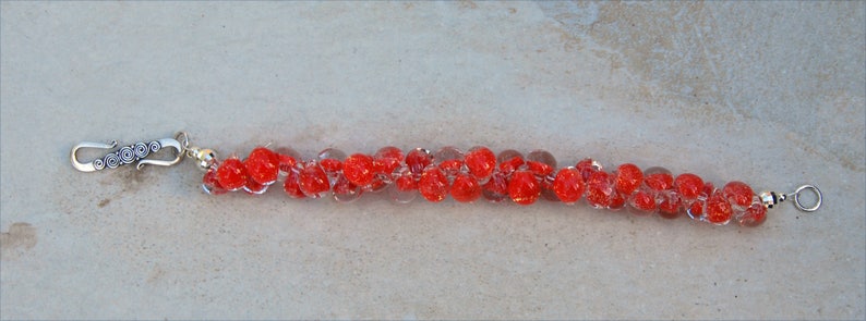 May include: A red glass bead bracelet with silver clasps. The beads are clear with red flecks.