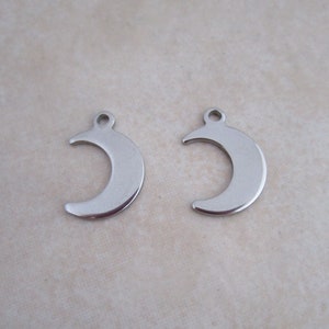 May include: Two silver crescent moon charms with a hole at the top for attaching to jewelry or other crafts.