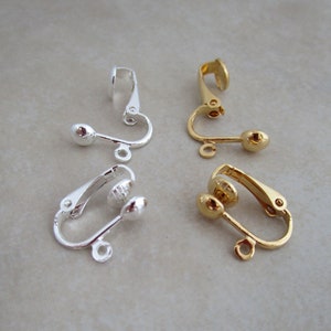 May include: Four earring clips, two silver and two gold, with a small ball on each end. The clips are designed to attach to the ear without piercing.