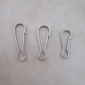 May include: Three silver key rings of different sizes. The key rings are made of metal and have a simple, classic design.