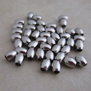 Cuentas de acero inoxidable de 5 mm x 4 mm con cuerpo ovalado hipoalergénico.
