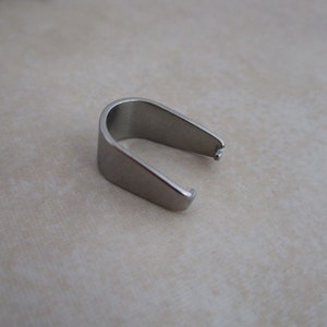 May include: A silver metal pendant bail, a small loop used to attach a pendant to a chain or cord.