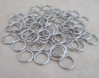 May include: A pile of silver jump rings, a type of metal ring used in jewelry making.