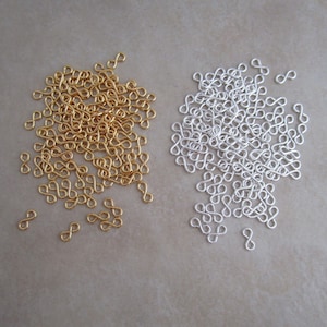 May include: A large pile of gold-colored infinity loop connectors and a smaller pile of silver-colored infinity loop connectors.