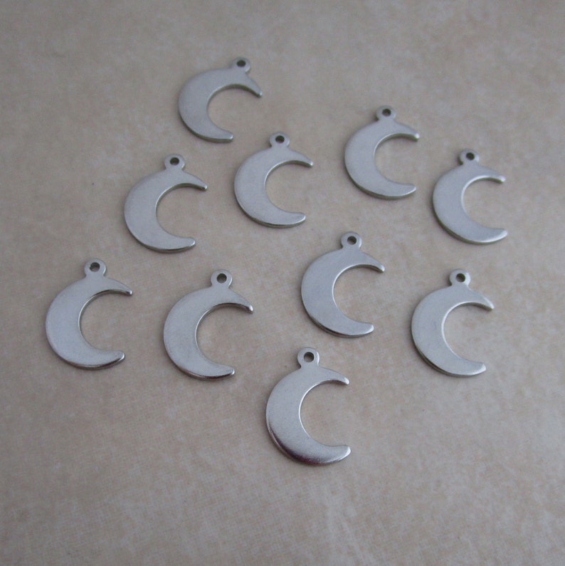May include: Ten silver crescent moon charms with a hole at the top for attaching to jewelry or other crafts.