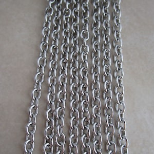 May include: A close-up of a silver chain with multiple strands. The chain is made of small, round links.