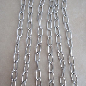 May include: A silver-toned metal chain featuring a series of uniform, elongated oval links. The chain is arranged in multiple vertical strands, showcasing a smooth, polished finish and a consistent, repeating pattern throughout the entire length.