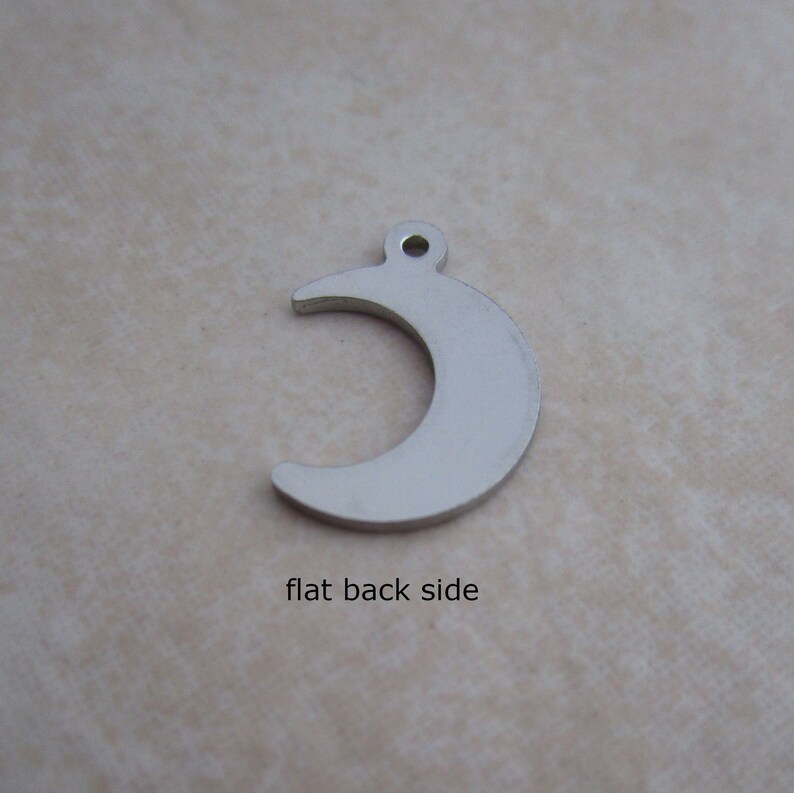 May include: Silver crescent moon charm with a flat back side.