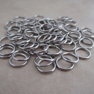 Puede incluir: Un mont&oacute;n de anillos de salto de plata, un tipo de anillo de metal utilizado en la fabricaci&oacute;n de joyas.