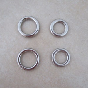 May include: Four silver metal rings of different sizes. The rings are smooth and shiny.