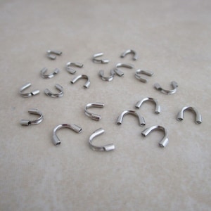 May include: A collection of silver-toned metal crimp beads, used for jewelry making.