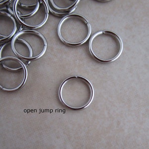 Puede incluir: Primer plano de un mont&oacute;n de anillos de salto abiertos plateados. Los anillos son peque&ntilde;os y redondos, y son perfectos para la elaboraci&oacute;n de joyas.