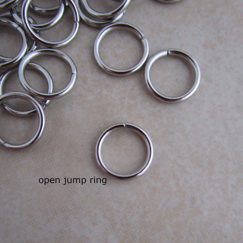 Puede incluir: Primer plano de un mont&oacute;n de anillos de salto abiertos plateados. Los anillos son peque&ntilde;os y redondos, y son perfectos para la elaboraci&oacute;n de joyas.