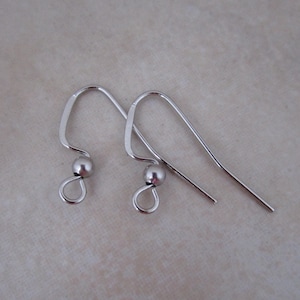 May include: Two silver-colored earring hooks. Each hook has a curved top, a small silver bead, and a loop at the bottom. The hooks are designed for pierced ears and are displayed against a neutral background.