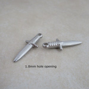 Op de afbeelding: Twee zilveren dolkbedels met een getextureerd oppervlak. Elke bedel heeft een opening van 1,8 mm.