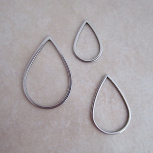 May include: Three silver teardrop-shaped metal hoops of varying sizes.