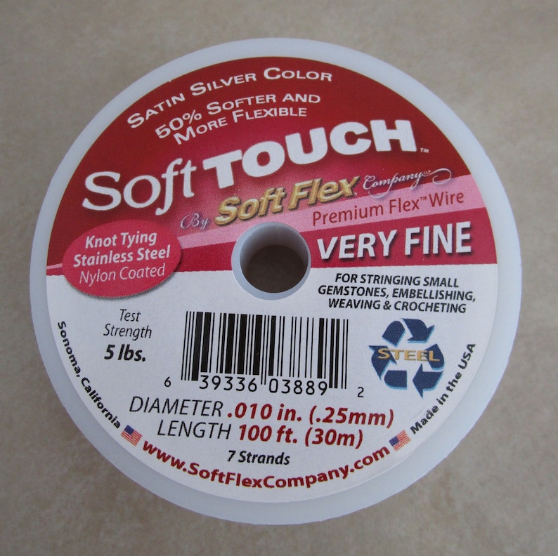 May include: A spool of Soft Touch Soft Flex Premium Flex Wire in silver color. The wire is very fine and has a test strength of 5 lbs. The spool is labeled with the brand name, product details, and a barcode. The wire is made in the USA.