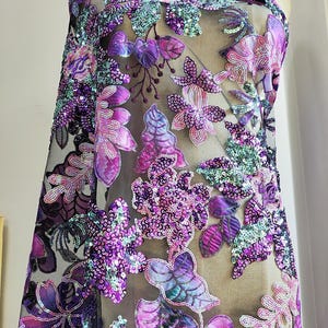 Bellissimo tessuto con paillettes floreali nei toni del viola, tessuto a rete nero ricamato con fiori per abiti da ballo, abiti da cerimonia, costumi, cucito di abbigliamento