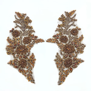 May include: Two gold and brown beaded floral appliques with a delicate mesh backing. The appliques are perfect for adding a touch of elegance to any garment or craft project.
