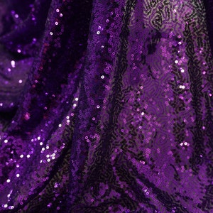 Puede incluir: Tela de lentejuelas de color morado con un acabado brillante e iridiscente. Las lentejuelas están densamente empaquetadas y crean un efecto brillante.