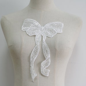 Puede incluir: Aplique de lazo de cuentas blancas para coser o manualidades. El lazo está hecho de cuentas blancas y tiene un diseño delicado y femenino.