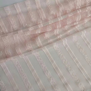 Può includere: Tessuto di pizzo rosa a righe con un delicato motivo floreale. Il tessuto è trasparente e ha una texture morbida e fluida.