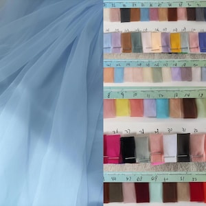 May include: A light blue tulle fabric draped on the left side of the image. On the right, a color swatch chart displays numerous fabric samples in various colors, arranged in rows and columns, with numbers along the top and sides.