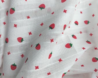 May include: White fabric with a repeating pattern of red strawberries and small red crosses. The fabric has a subtle grid pattern.