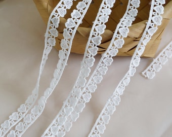 May include: White lace trim with a delicate heart pattern. The trim is shown in a basket and on a white background.