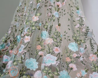 May include: Pale green tulle fabric with embroidered floral designs in shades of pink, blue, and peach.