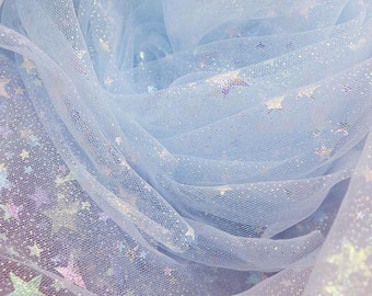 Pode incluir: Tecido de tule azul claro com lantejoulas iridescentes em forma de estrela espalhadas por todo o tecido.
