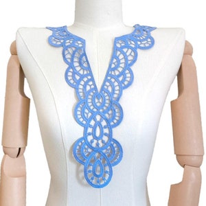 Könnte beinhalten: Hellblaue Spitzenborte mit V-Ausschnitt. Die Borte ist aus zarter, filigraner Spitze gefertigt und eignet sich perfekt, um jedem Kleidungsstück einen Hauch von Eleganz zu verleihen.