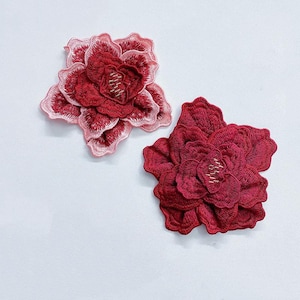 May include: Two embroidered fabric flower patches. One is pink and red, the other is a deep red.