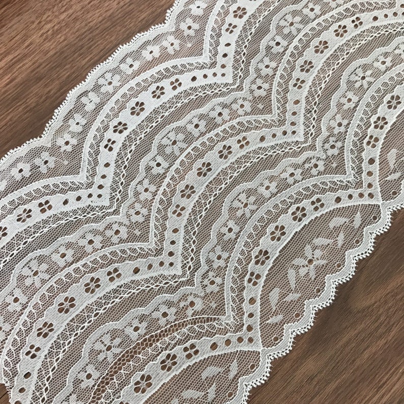 May include: White lace trim with a scalloped edge and a delicate floral pattern.