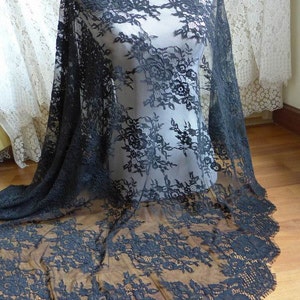 May include: Black lace fabric with a floral pattern. The lace is delicate and has a scalloped edge.