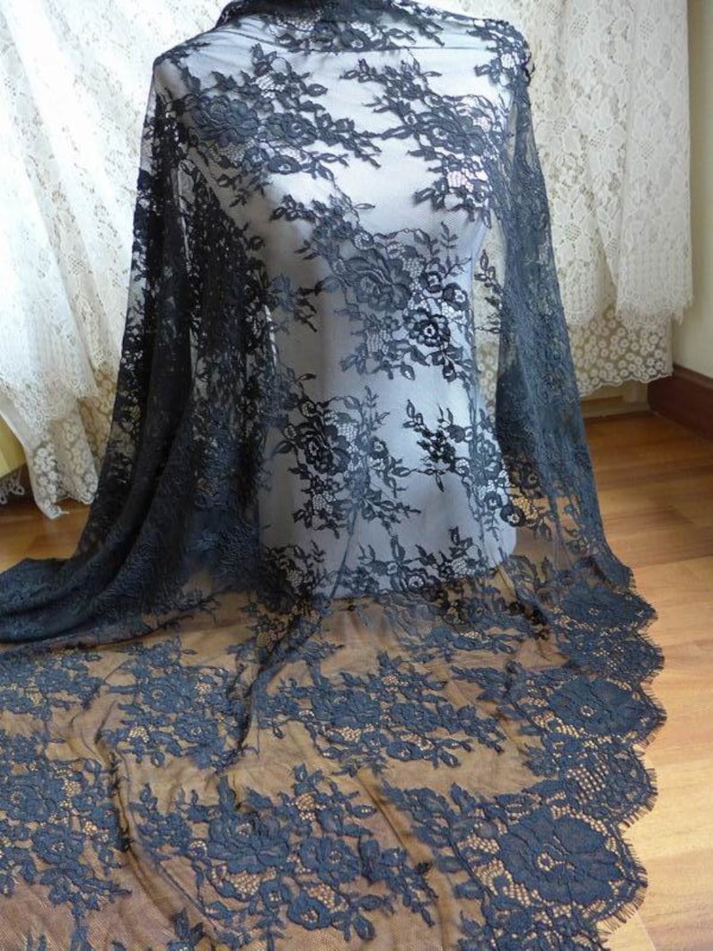 May include: Black lace fabric with a floral pattern. The lace is delicate and has a scalloped edge.