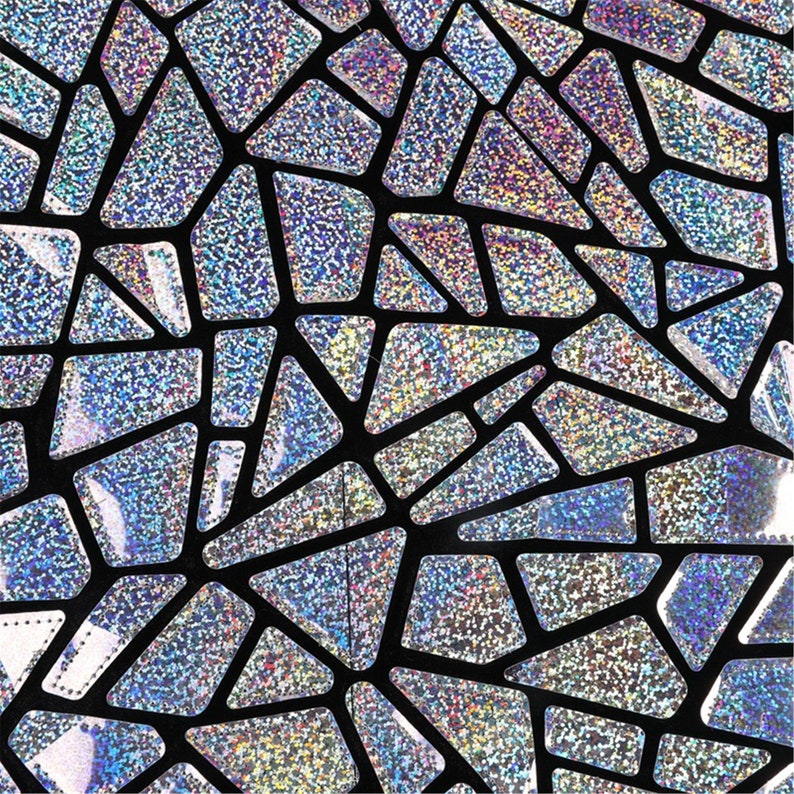 K&ouml;nnte beinhalten: Ein schwarzer Stoff mit einem silbernen holografischen Muster aus geometrischen Formen. Das Muster besteht aus kleinen, schimmernden Quadraten, die einen schimmernden Effekt erzeugen.