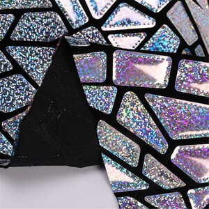 K&ouml;nnte beinhalten: Schwarzer Stoff mit einem geometrischen Muster aus irisierendem silbernem Glitzer. Der Stoff hat einen dezenten Glanz und eine strukturierte Oberfl&auml;che.
