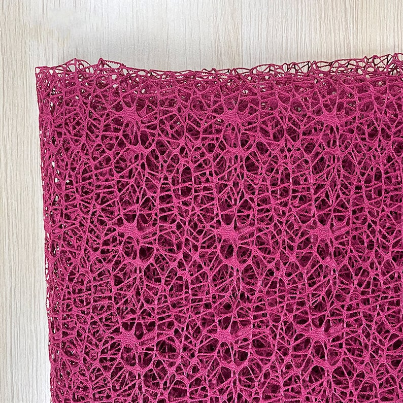 May include: A close-up of a deep pink, delicate, mesh fabric with a fine, intricate pattern. The fabric is soft and airy, with a slightly textured surface.