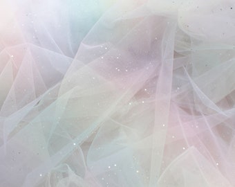 May include: A sheer, iridescent fabric with a rainbow ombre effect and silver glitter throughout.
