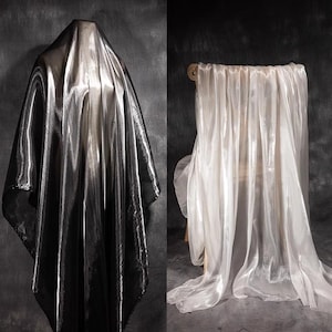 May include: A split image showing two pieces of fabric. On the left, a dark charcoal grey, metallic, shimmering fabric draped over a form. On the right, a sheer, translucent, off-white fabric with a glossy finish draped over a wooden chair.