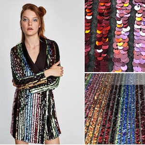May include: A black sequined dress with a rainbow stripe pattern. The dress has a long sleeve and a wrap style. The fabric is made of sequins on a mesh base.